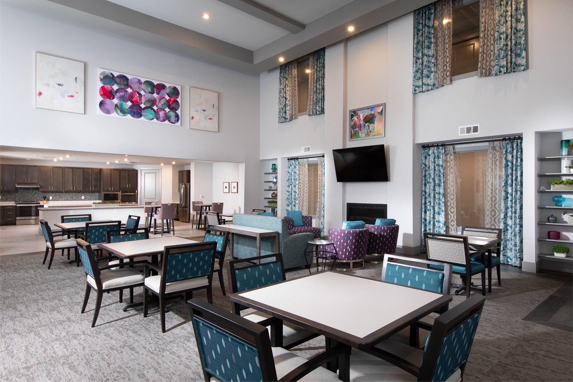 an open concept dining room with a sitting area and television at a senior apartment community